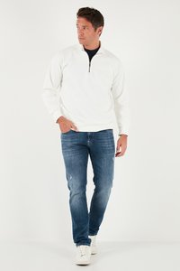 Valge neljandikibli sweatshirt, pehme kangas, raglanvarrukad, kombinatsioon siniste kulunud teksade ja valgete tossudega. Lihtne, kaasaegne vabaaja riietus.