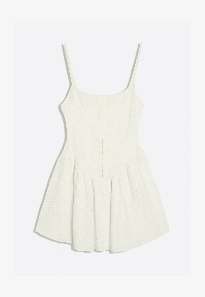 Robe blanche sans manches avec fines bretelles, corsage ajusté et jupe évasée en tissu texturé.