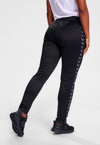 Zwarte sportpants met een rekbare tailleband, voorzien van een visgraatpatroon aan de zijkanten. Gladde, lichtgewicht stof met een tapered fit.