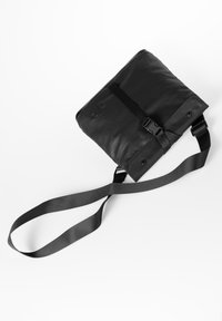 Borsa a tracolla nera realizzata in materiale testurizzato, con chiusura a fibbia, tracolla regolabile e logo in rilievo sulla parte anteriore.