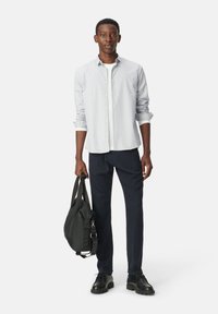 Lichtblauw gestreepte button-up shirt, zwarte broek, zwarte schoenen en een zwarte tas. Slim fit, gladde stof, opgerolde mouwen, minimalistisch ontwerp.