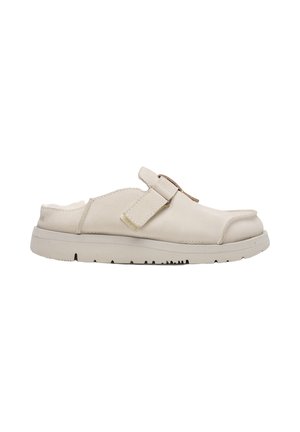 Sandalia beige tipo slip-on con una amplia correa ajustable en la parte superior, suela acolchada y diseño de puntera cerrada y redondeada.