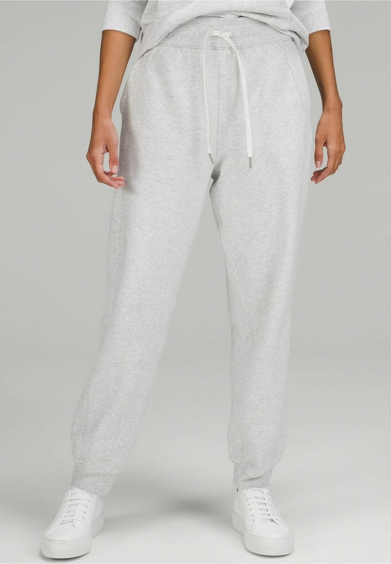 Grau Sweatpants aus weicher Baumwolle mit Kordelzugbund. Schmal zulaufendes Bein-Design mit elastischen Bündchen und seitlichen Taschen. Kombiniert mit weißen Sneakern.