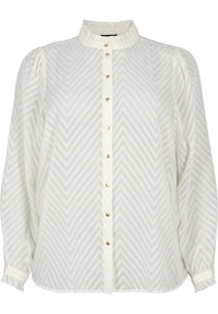 Bílá halenka s volánovým vysokým límcem, zapínáním na knoflíky vpředu a jemným vzorem ve tvaru rybí kosti. Dlouhé rukávy s nařasenými manžetami a zlatými knoflíky.