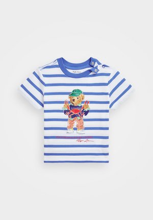 T-shirt a maniche corte a righe bianche e blu, con una grafica di un orso vestito in modo vivace e testo rosso nella parte inferiore.