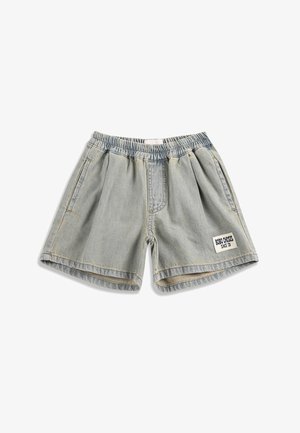 Hellblaue Jeansshorts mit elastischem Bund, Seitentaschen und einem weißen Aufnäher mit der Aufschrift "BOBO CHOSES SINCE '09" am linken Bein.