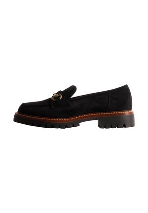 Mocassin en daim noir avec semelle cousue marron et semelle épaisse, avec un petit détail de boucle métallique sur le dessus.