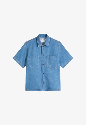 Chemise en jean bleu clair à manches courtes avec boutons, deux poches plaquées avant et un col, étalée à plat sur un fond blanc.
