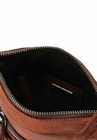Interno di una borsa in pelle marrone con una cerniera, rivestimento nero. Dettagli importanti includono una tasca per carte e una texture liscia.