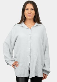 Camicia grigia chiaro con bottoni realizzata in tessuto testurizzato a motivo sottile, dotata di un colletto e vestibilità rilassata. Maniche lunghe con bottoni.