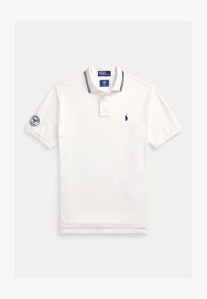 Polo blanco de manga corta con detalles en azul marino, logo de Ralph Lauren en el pecho y parche del torneo de tenis de Wimbledon en la manga izquierda.