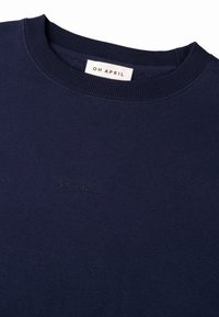 Felpa di un blu navy scuro con collo rotondo a costine, caratterizzata da un logo ricamato con filo abbinato. Texture liscia e vestibilità comoda.