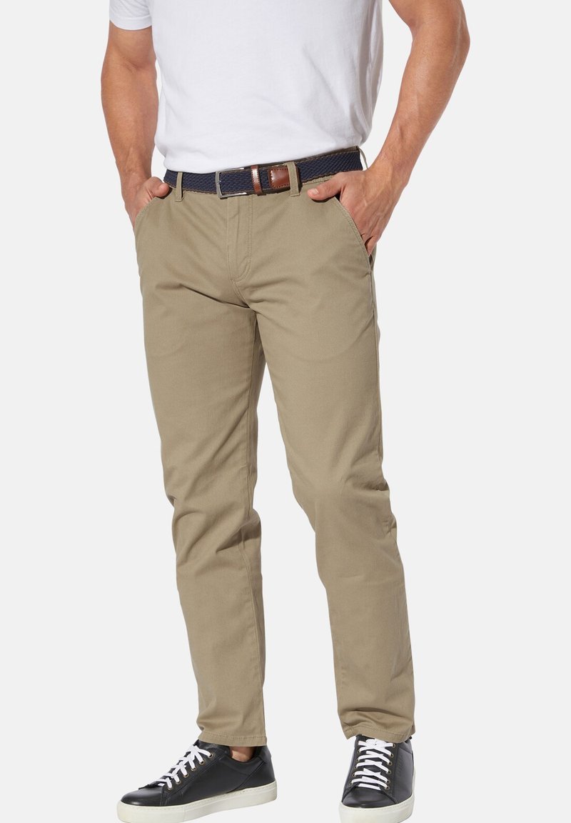 Beige cotton pants with a straight fit, featuring side pockets and a dark woven belt with a brown leather accent. Paired with black sneakers.