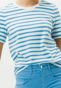 Raidallinen t-paita valkoisena ja vaaleansinisena, valmistettu pehmeästä puuvillasta. Pyöreä pääntie ja lyhyet hihat. Yhdistetty vaaleansinisiin farkkuihin, joissa on etupainike.