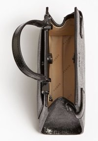 Borsa nera con trama, forma strutturata, dettagli in metallo lucido e interno beige con il logo 'GUESS'. Design a apertura superiore.