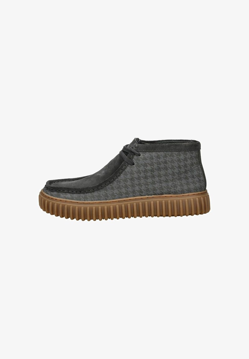Bottine en tissu gris avec un motif pied-de-poule texturé, bout arrondi, et une semelle en caoutchouc marron flexible avec des détails rainurés.