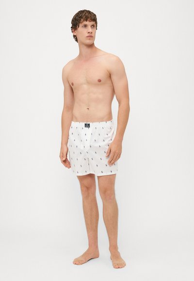 Witte boxershorts met een klein marineblauw patroon, elastische tailleband en een klein logo-label aan de voorkant, gemaakt van lichtgewicht stof.