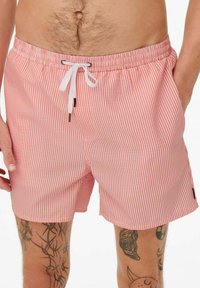 Shorts de bain rayés en rose clair et blanc, dotés d'une taille élastique avec cordon de serrage et de poches latérales. Longueur de jambe courte.