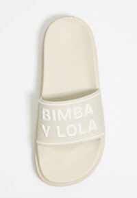 Beezhse slippel, millel on tekstureeritud pealis, valge reljeefne kiri "BIMBA Y LOLA" rihmal, ümar kuju ja lamedat talla.