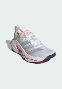 Lekkie buty sportowe w białym i jasnoróżowym kolorze. Posiadają oddychający mesh, trzy szare paski oraz teksturowaną różową podeszwę z zygzakowatym wzorem.