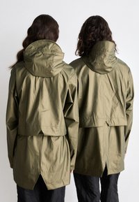 Olive green, waterproof jackets with hoods; relaxed fit, layered back design, and visible stitching details. Smooth, shiny texture.