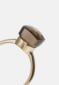 Bague en or avec une grande pierre précieuse quartz fumé facettée montée en sertissage clos sur un fond blanc.