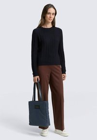 Meresinine soonikootud kampsun, pruunid laiade säärega püksid ja mustade käepidemetega sinine tikitud kandekott. Komplekti lõpetavad neutraalse tooniga tossud.