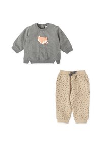 Sudadera gris con un gráfico de un zorro en el frente, combinada con pantalones beige estampados con bolsillos y cintura con cordón.