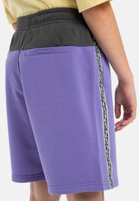 Paarse zwembroeken met een grijze elastische tailleband, zijzakken en een decoratieve zwart-witte gestreepte baan langs de zijkant.