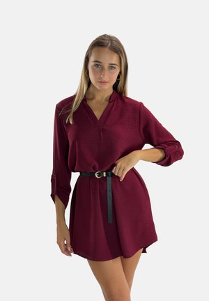 Abito bordeaux con scollo a V e maniche lunghe, caratterizzato da polsini arrotolati e una cintura nera in vita, realizzato in tessuto morbido e testurizzato.
