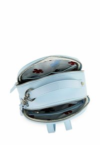 Světle modrá kabelka se dvěma otevřenými stříbrnými zipy, která odhaluje interiér s barevným květinovým vzorem a několika přihrádkami.