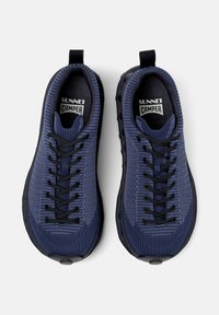 Mörkblå sneakers med texturerat tyg, svarta snören och en svart gummisula, placerade sida vid sida mot en vit bakgrund.