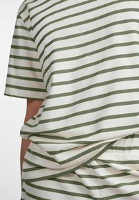 Camiseta a rayas con franjas alternas en verde oscuro y blanco, de manga corta, corte holgado y detalle de nudo en el frente. Textura de tela suave.