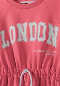Korálově růžová mikina s bílým textem "LONDON" a doplňkovým písmem. Obsahuje šňůrku na stažení v pase a vroubkovaný výstřih. Měkká tkanina.