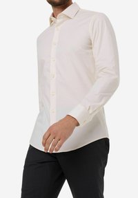 Crème button-up shirt met een klassieke kraag, lange mouwen en knoopmanchetten. Gemaakt van een soepele stof met een subtiele glans en een getailleerde pasvorm.