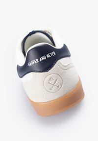 Zapatilla con un cuerpo de ante blanco, talón de cuero azul marino y suela de goma. Presenta un logo en relieve y el texto "HARPER AND NEYER" en el talón.