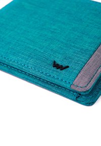 Teal fabric wallet with a gray accent and black logo. Features a textured surface and stitched edges for durability. Slim rectangular shape.