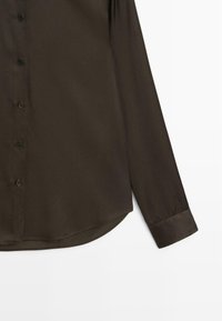 Camicia a maniche lunghe marrone scuro con chiusura a bottoni, dalla texture liscia e orlo arrotondato con polsini abbottonati.