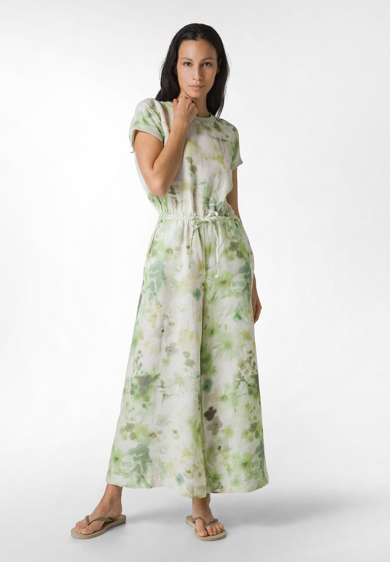 Jumpsuit de estampado floral en verde y blanco con mangas cortas, cintura ajustable con cordón y diseño de piernas anchas. La tela parece ligera y texturizada.