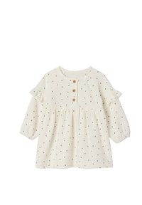 Kleid in Cream mit schwarzem Punktemuster, rundem Ausschnitt, drei Holzknöpfen, Rüschenschultern und gerafftem Taillenbereich, aus weichem Stoff gefertigt.