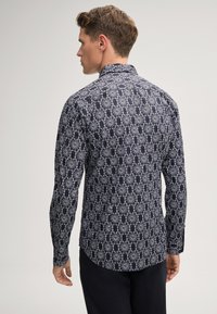 Langarmshirt in marineblauw met een gedetailleerd wit bloemenpatroon, klassieke kraag, knoopmanchetten en een licht afgeronde zoom.