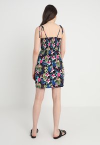 Blumiges Sommerkleid mit einem gerafften Oberteil, verstellbaren Trägern und lebendigen Farben auf dunklem Hintergrund. Verfügt über einen gerafften Rock.