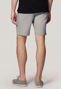 Szare szorty z gładkiego, bawełnianego materiału, cięte powyżej kolana, w zestawie z szarymi zamszowymi butami. Prosty fason, bez widocznych wzorów.