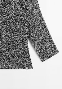 Black and white knit sweater featuring a textured pattern, three-quarter sleeves, and a slightly tapered hem.