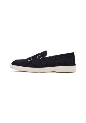 Marineblaue Wildleder-Halbschuhe mit einem Slip-On-Design, ausgestattet mit zwei silbernen Schnallen und einer kontrastierenden weißen Gummisohle. Glatte Textur, runde Zehenform.