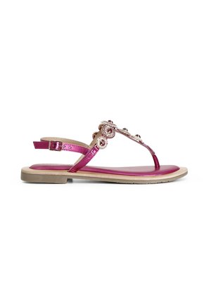 Flad lyserød sandal med metalliske stropper og dekorative cirkulære rhinsten, med justerbar ankelspænde og beige sål.