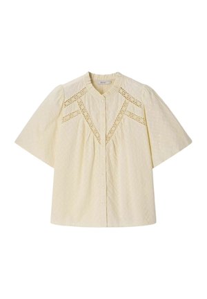Crèmekleurige blouse met korte mouwen, knopen aan de voorkant, gerimpelde kraag, opgepofte schouders en kanten details die geometrische patronen op de borst vormen.