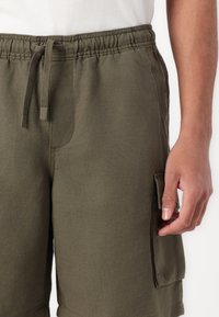 Khaki cargo shorts med elastisk talje og justerbar snor. Har sidelommer og blødt, struktureret stof.