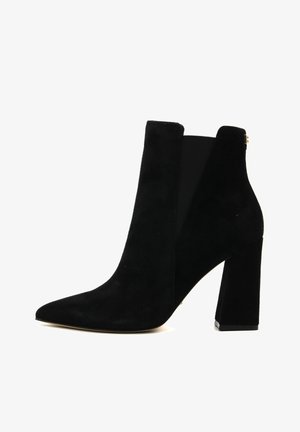 Bottine en daim noir avec bout pointu et talon carré, dotée d'un panneau élastique sur le côté et d'un petit logo doré près du haut.