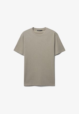 T-shirt corto a maniche corte color beige chiaro realizzato in cotone morbido. Presenta un colletto rotondo e un design semplice e privo di decorazioni. Vestibilità classica.